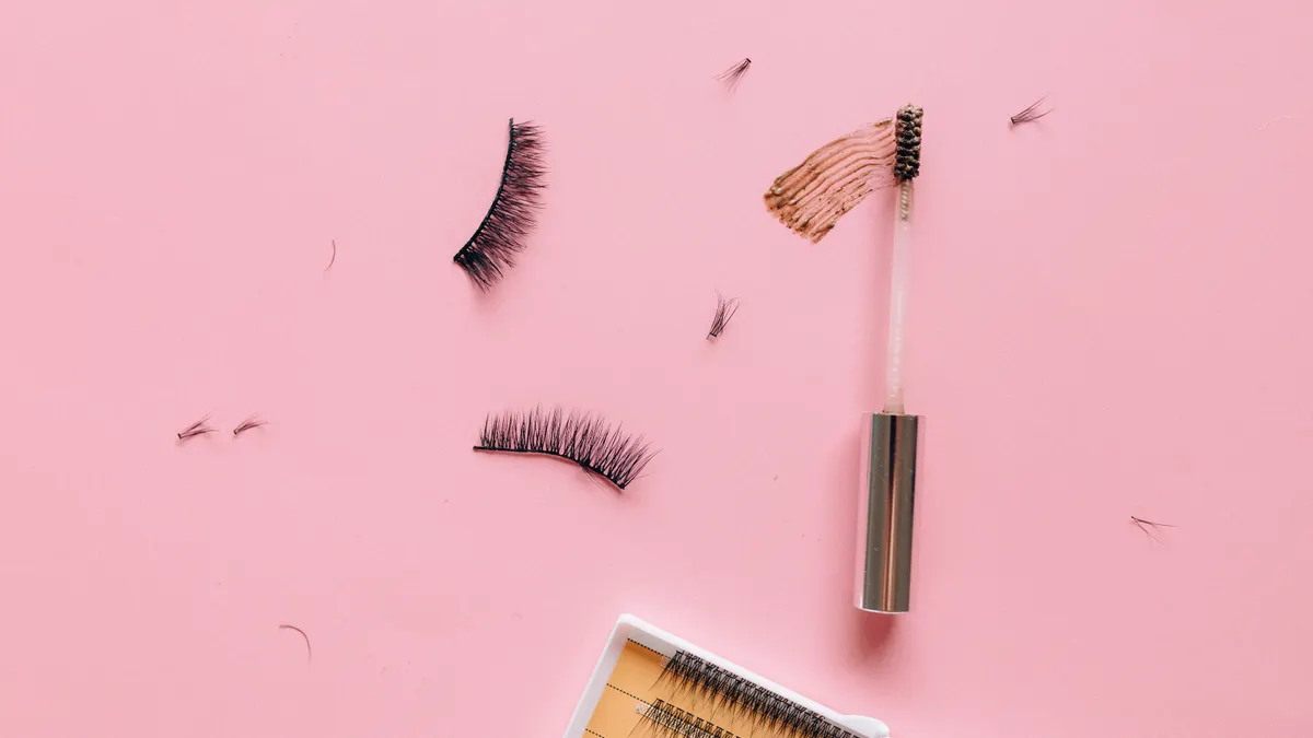 False lashes, mascara wand, and lash tray on pink background