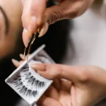 Technician applying eyelash extensions with tweezers