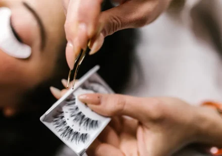 Technician applying eyelash extensions with tweezers