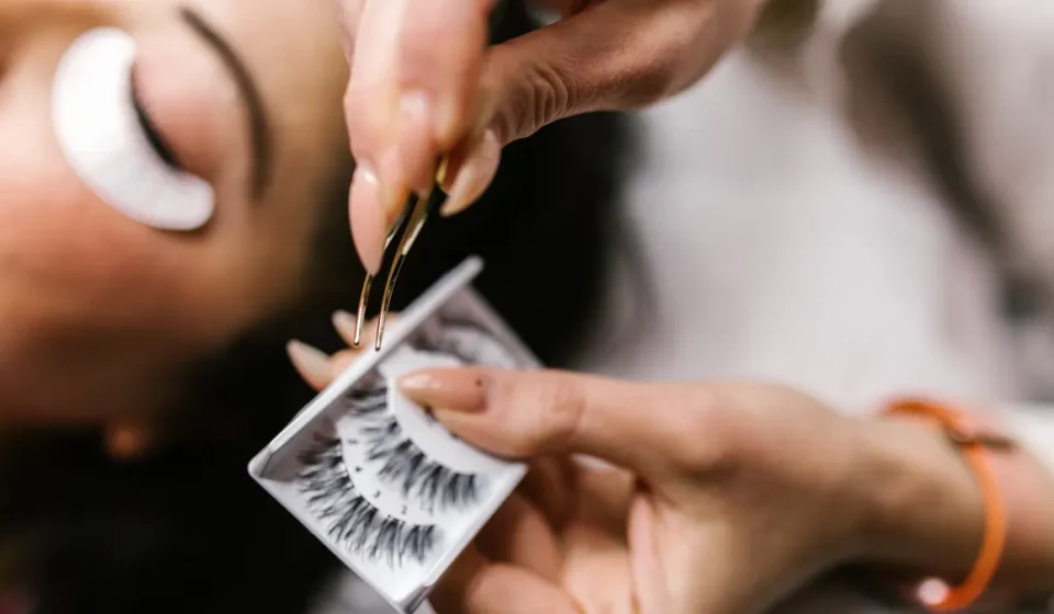 Technician applying eyelash extensions with tweezers
