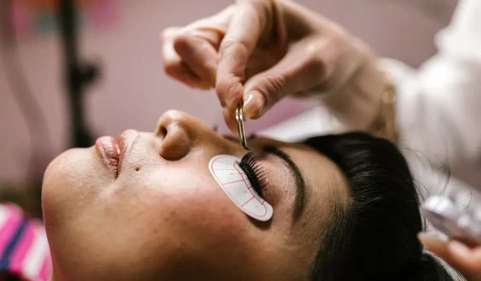 Technician applying eyelash extensions to a client's eye