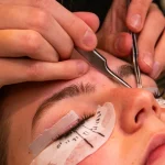 Lash technician applying eyelash extensions with tweezers