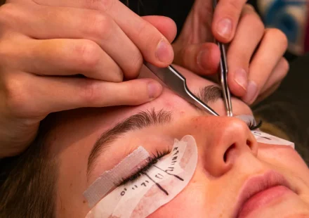 Lash technician applying eyelash extensions with tweezers