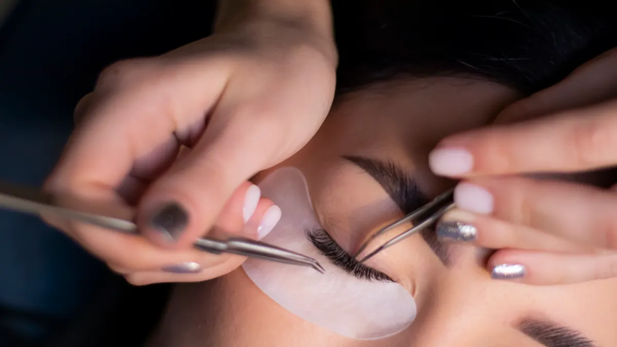 How Lash Extensions Are Applied: Step-by-Step for First-Timers Tweezers placing lash extensions over eye pads